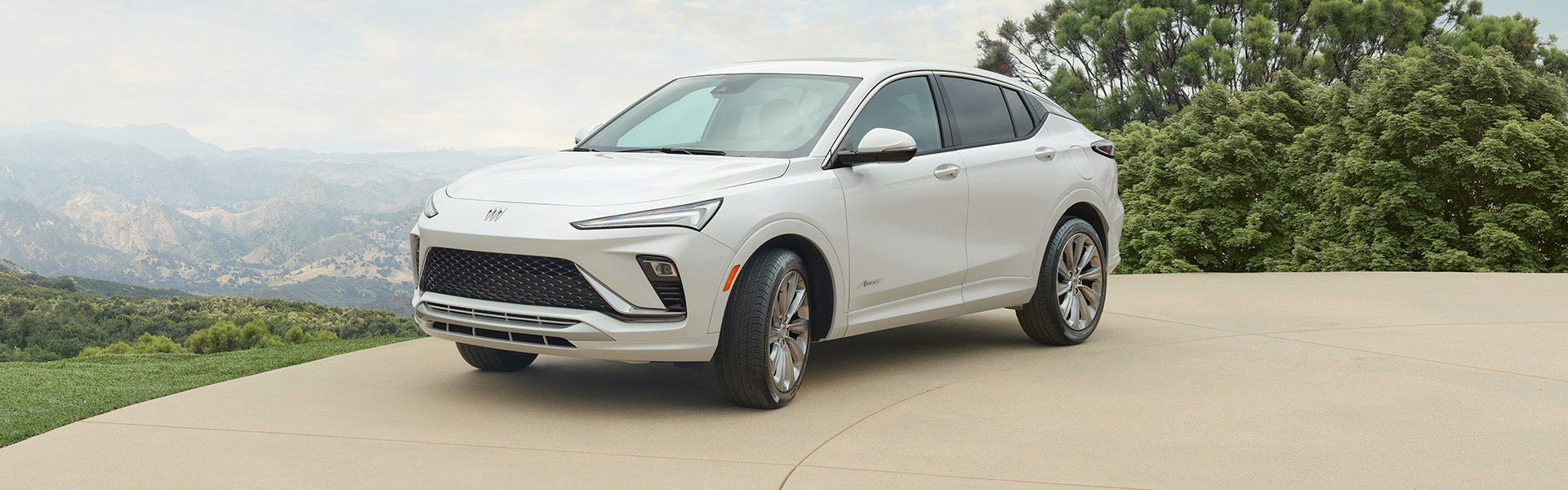 A white 2024 Buick Envista parked on the hill with a mountain view