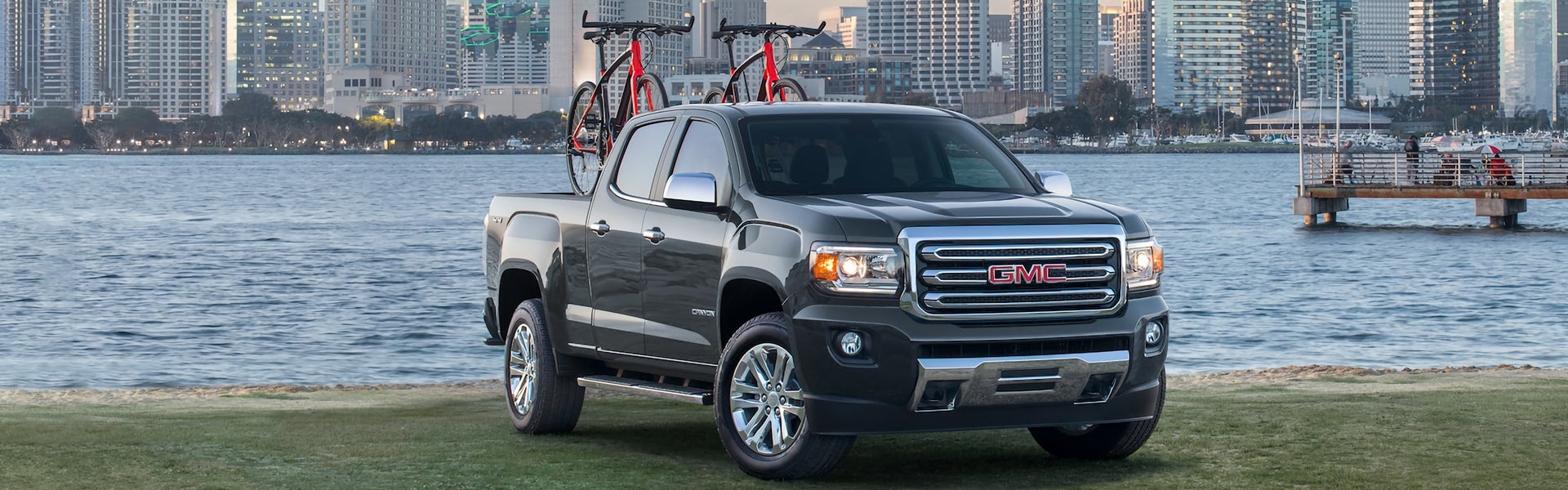 black GMC Canyon at a park with to bicycles in the truck bed