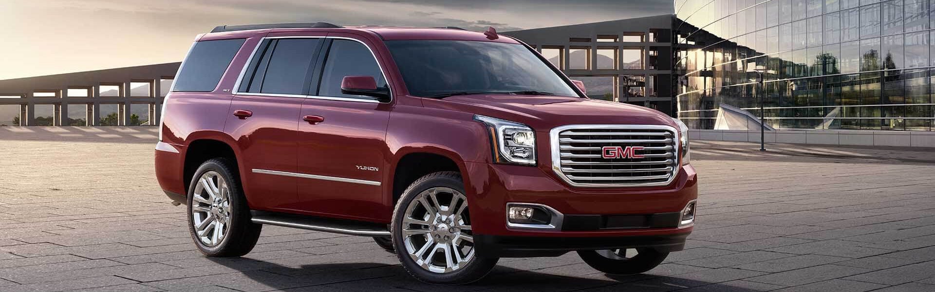 A Red GMC Yukon parked at a convention center at sunset